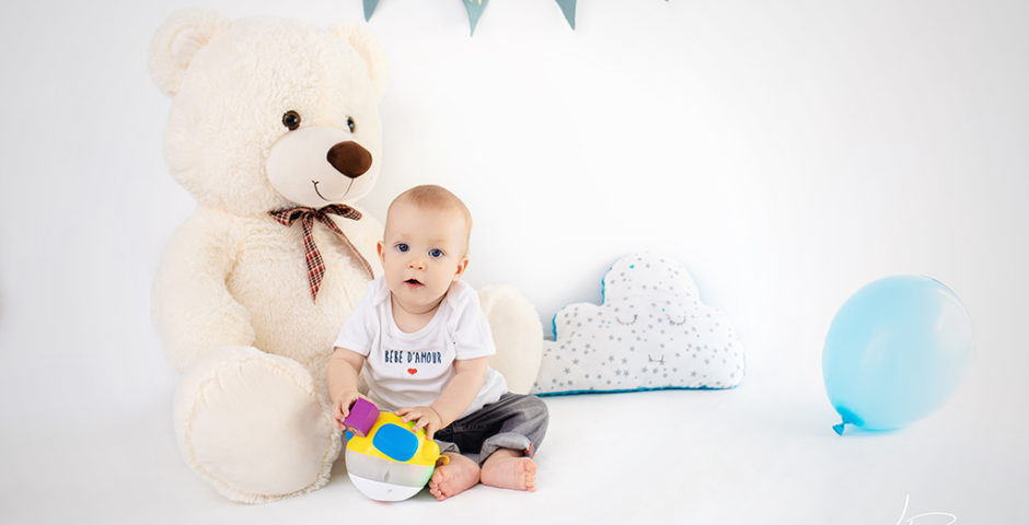 lifestyle bébé grandit 9 mois gars fond blanc fanions nounours